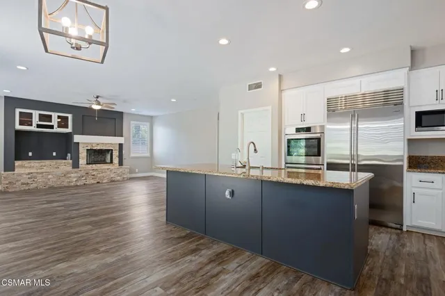 a large kitchen with stainless steel appliances granite countertop a stove and cabinets