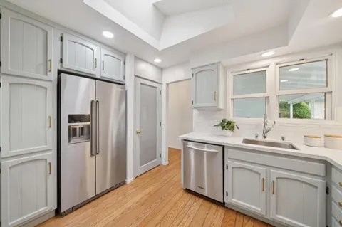 a kitchen with stainless steel appliances granite countertop a sink a stove and a wooden floors