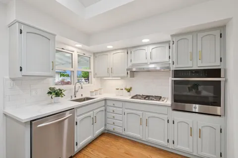 a kitchen with white cabinets white appliances and sink