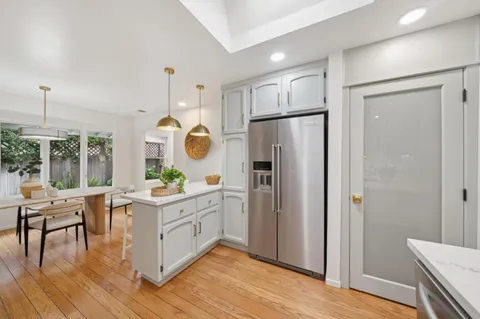 a kitchen with white cabinets and wooden floors