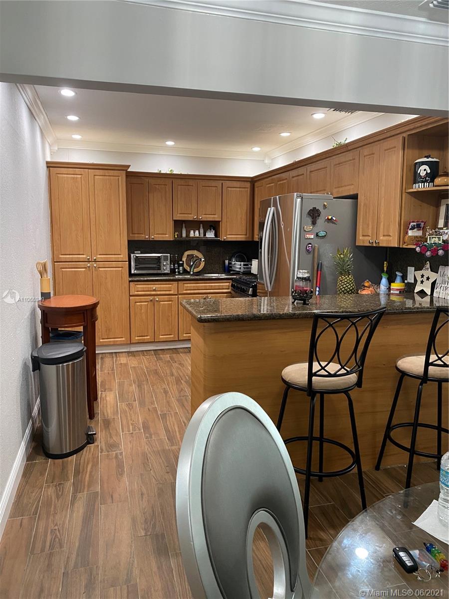 7565 Southwest 28th Street Road Miami, FL 33155 - Photo 28 of 31 a kitchen with stainless steel appliances granite countertop a stove top oven a sink a dining table and chairs with wooden floor