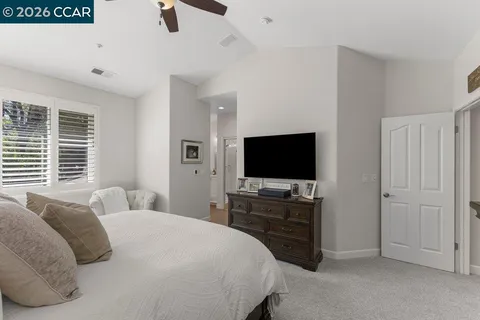 a bedroom with a bed and a flat tv screen on dresser