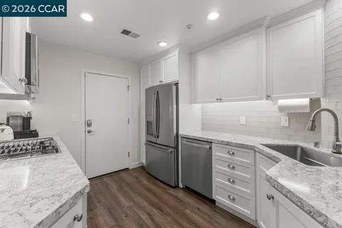a kitchen with granite countertop a sink stove and refrigerator