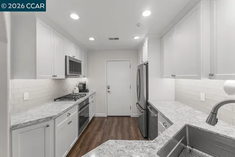 a kitchen with granite countertop a sink stainless steel appliances and cabinets