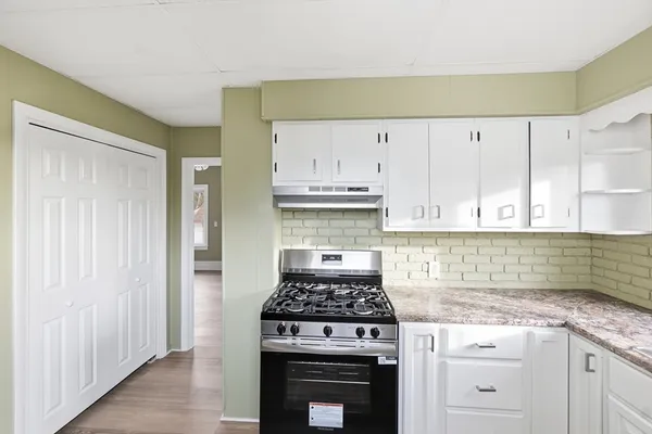 a kitchen with granite countertop a stove and white cabinets
