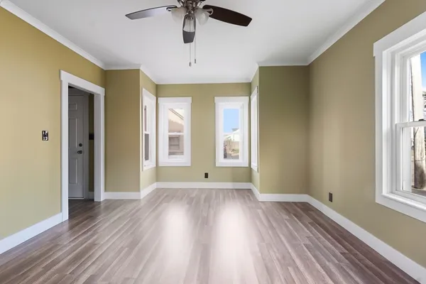 a view of an empty room with a window and wooden floor