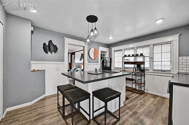 a kitchen with stainless steel appliances granite countertop a stove a sink dishwasher and a dining table with wooden floor