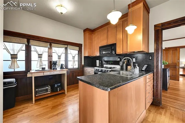 a kitchen with stainless steel appliances granite countertop a sink a stove and a wooden floors
