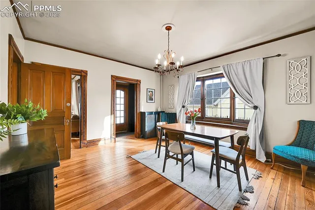a dining room with wooden floor a chandelier a wooden table and chairs