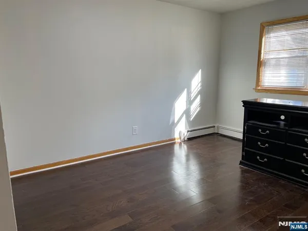 an empty room with wooden floor cabinet and windows
