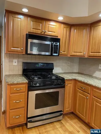 a kitchen with granite countertop wooden cabinets and stainless steel appliances