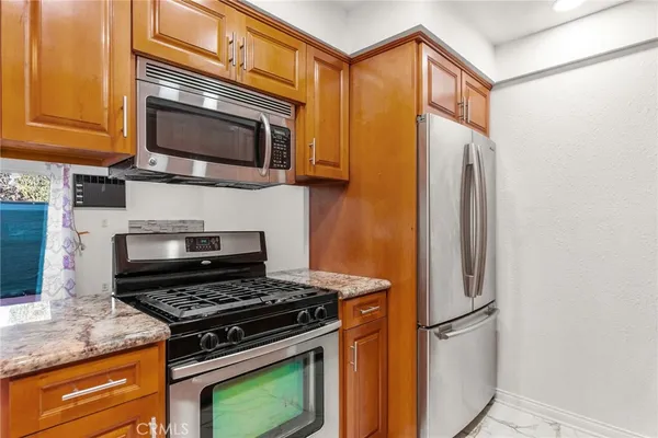 a kitchen with stainless steel appliances granite countertop a stove top oven microwave and refrigerator