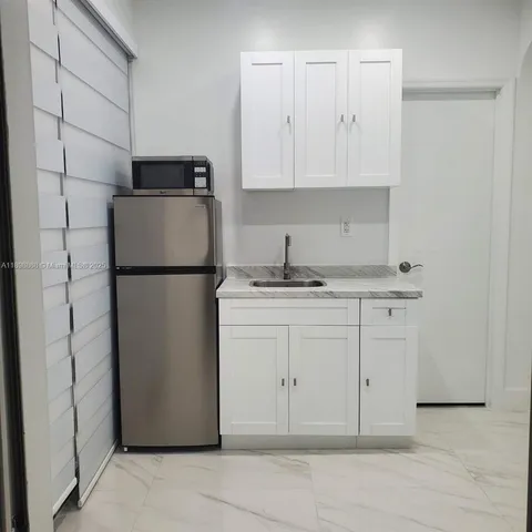 a kitchen with a refrigerator and white cabinets