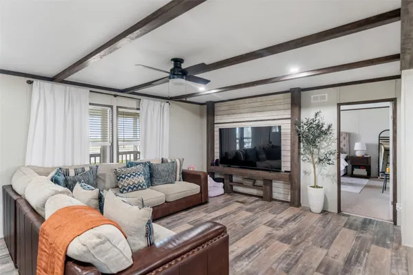a living room with stainless steel appliances a dining table wooden floor and a window
