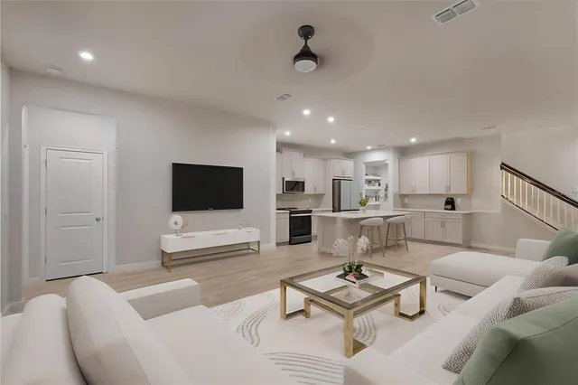 a living room with furniture a flat screen tv and kitchen view