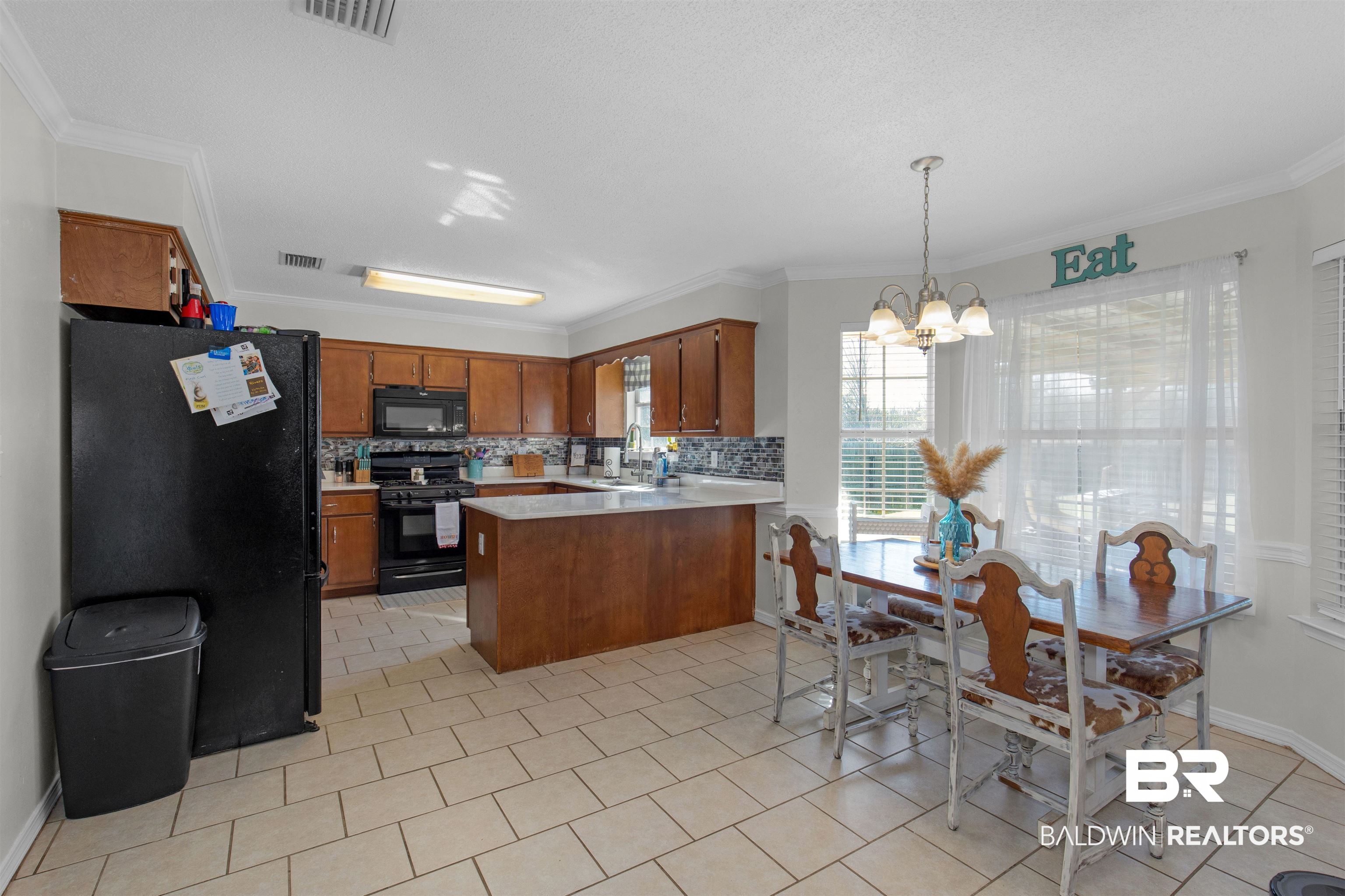 4950 Clealand Court Mobile, AL 36695 - Photo 6 of 20 Kitchen with a peninsula, a sink, light countertops, brown cabinets, and black appliances