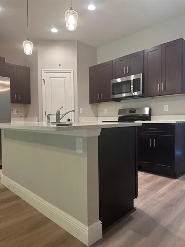 a kitchen with stainless steel appliances granite countertop a sink a stove a refrigerator and a oven with wooden floor