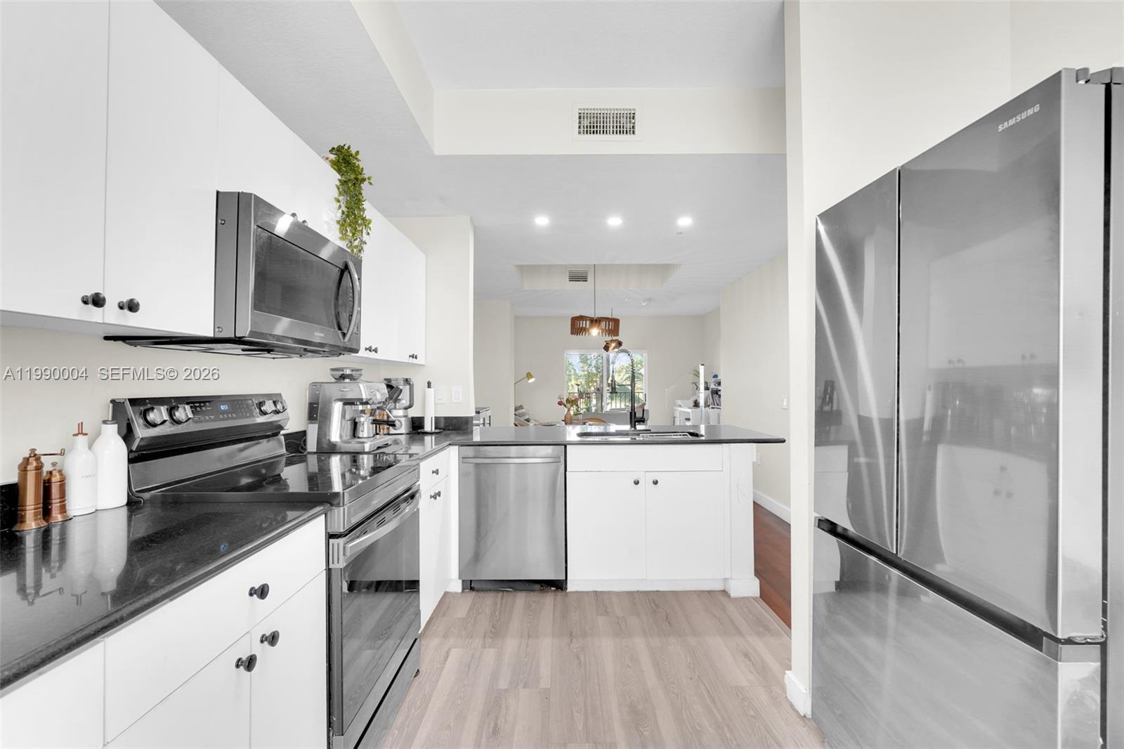 738 Northeast 90th Street, Unit 207 Miami, FL 33138 - Photo 6 of 31 a kitchen with stainless steel appliances a refrigerator sink and white cabinets