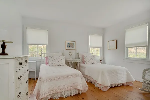 a spacious bedroom with two beds and wooden floor