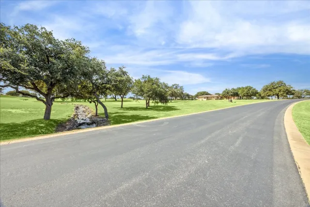 a view of a road with a yard and large trees
