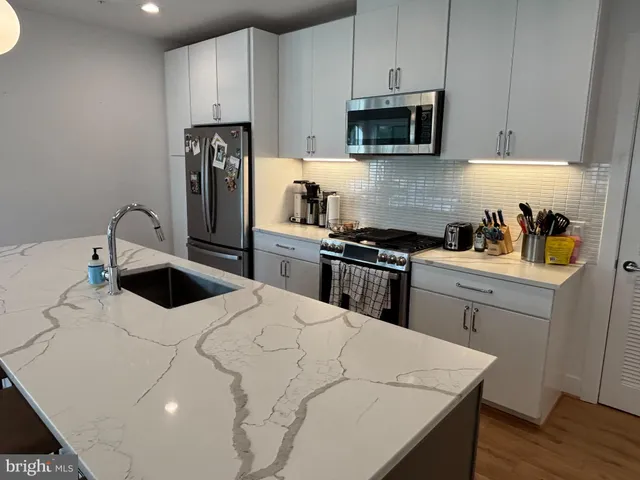 a kitchen with stainless steel appliances a stove a sink a microwave and cabinets