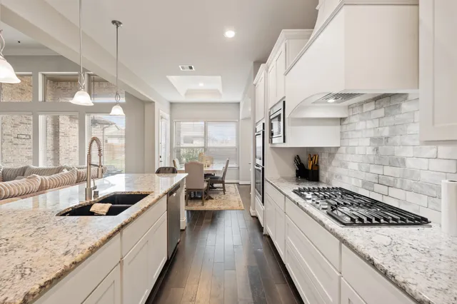 a kitchen with kitchen island granite countertop lots of counter top space a sink stainless steel appliances and cabinets