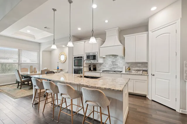 a kitchen with kitchen island granite countertop a table chairs sink and wooden floor