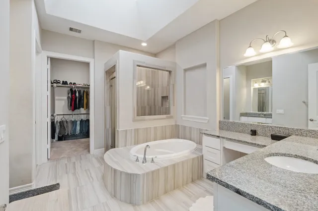 a spacious bathroom with a granite countertop tub sink and mirror