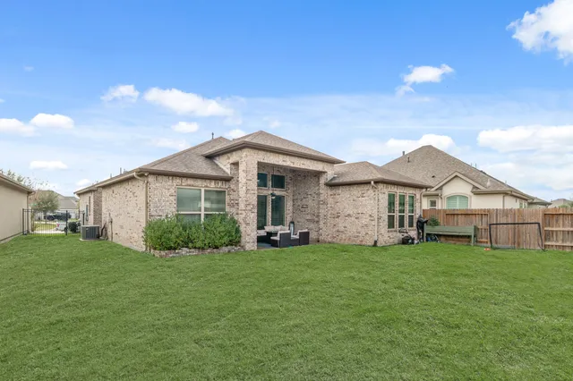 a view of a yard in front of a house with plants and large tree