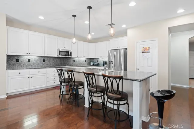 a kitchen with stainless steel appliances kitchen island granite countertop a table chairs and a refrigerator