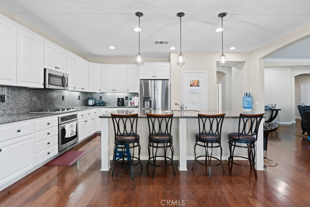 42914 Tomayo Street Indio, CA 92203 - Photo 4 of 31 a kitchen with stainless steel appliances granite countertop a kitchen island hardwood floor and a table