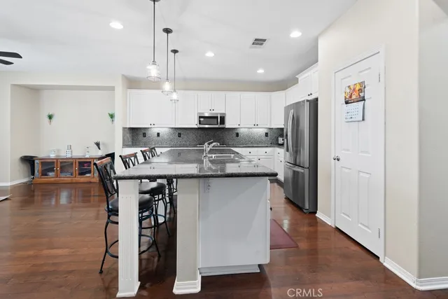 a kitchen with stainless steel appliances granite countertop a table chairs refrigerator and sink