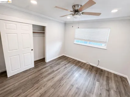 an empty room with wooden floor and ceiling fan