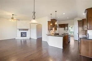 a large kitchen with stainless steel appliances kitchen island a stove a refrigerator a sink dishwasher and a fireplace with wooden floor