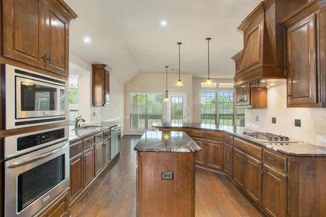 a kitchen with stainless steel appliances granite countertop a stove a sink and a microwave