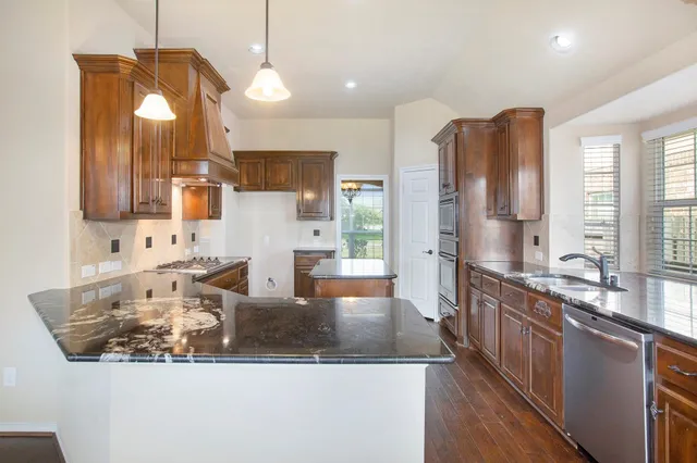 a kitchen with stainless steel appliances granite countertop a sink a stove and a refrigerator