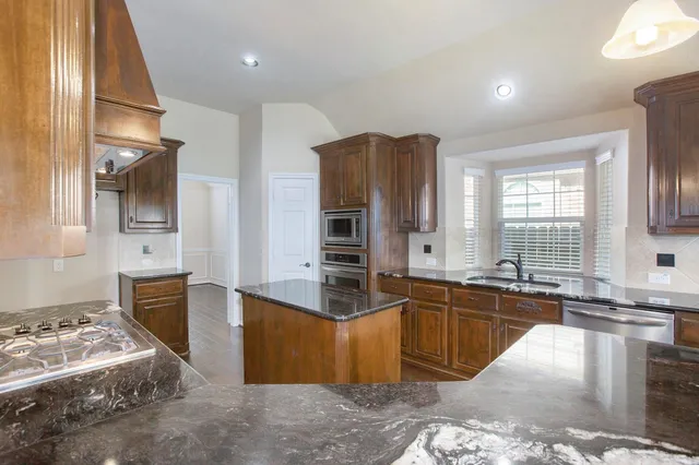 a kitchen with stainless steel appliances granite countertop a sink stove and refrigerator
