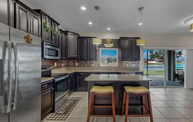 a kitchen with stainless steel appliances granite countertop a stove top oven a sink and a refrigerator