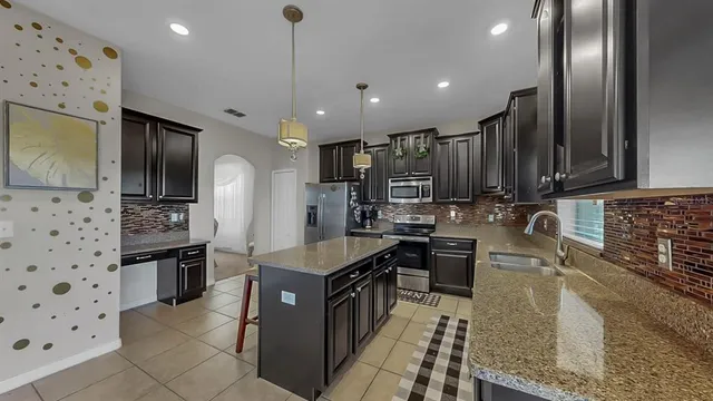 a kitchen with stainless steel appliances granite countertop a sink stove and refrigerator