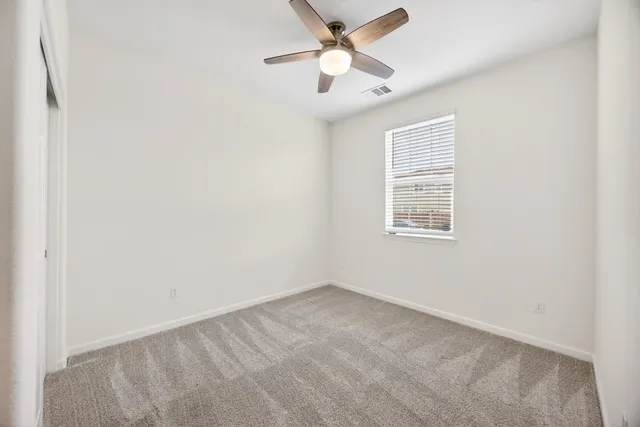 an empty room with a window and a fan