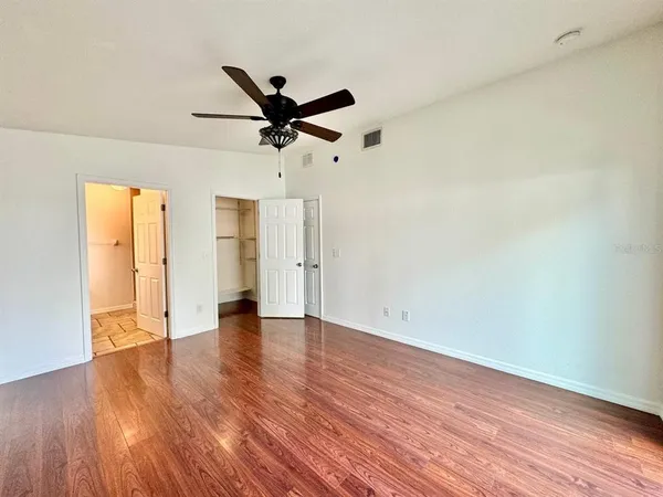 an empty room with wooden floor and a ceiling fan