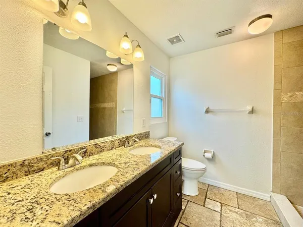 a bathroom with a granite countertop sink toilet and shower