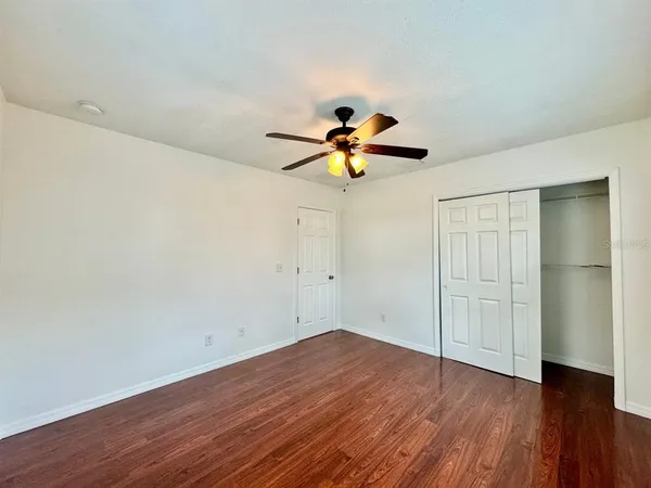 an empty room with wooden floor and a ceiling fan