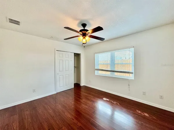 an empty room with wooden floor and windows