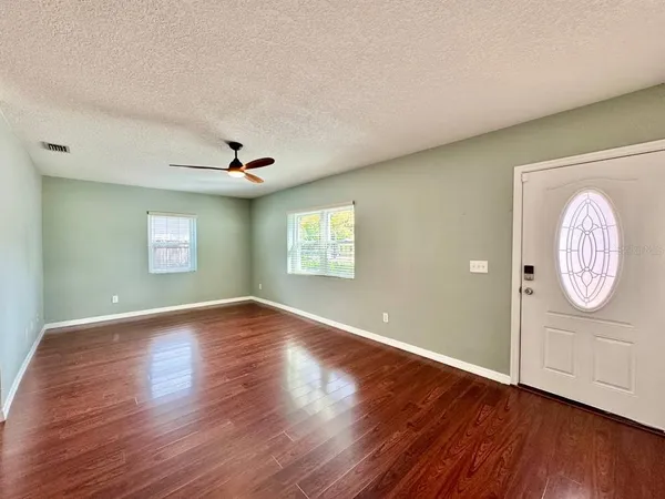 a view of an empty room with wooden floor and a window