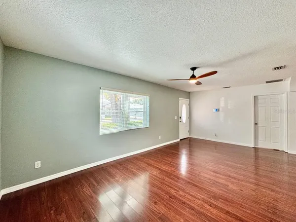 a view of an empty room with wooden floor and a window