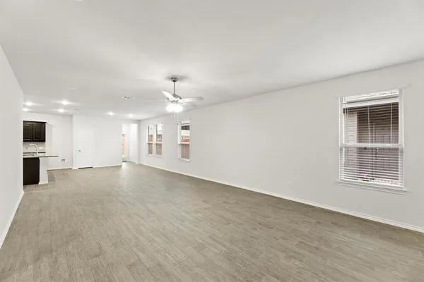 a view of an empty room with kitchen and window
