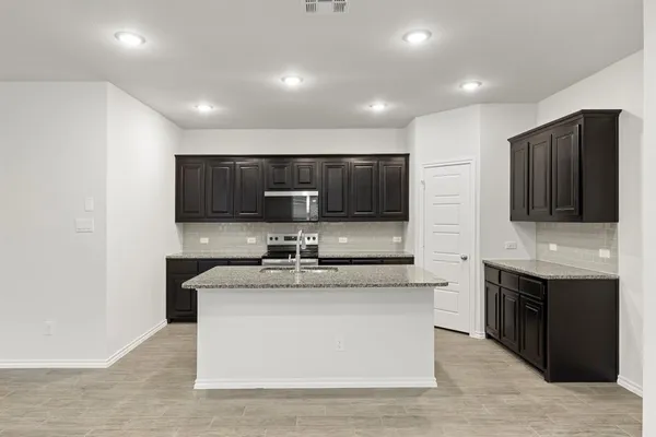 a kitchen with stainless steel appliances granite countertop a sink and a stove top oven with wooden floor
