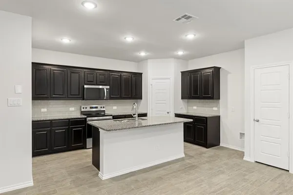 a kitchen with stainless steel appliances granite countertop a stove top oven a sink dishwasher a refrigerator and a microwave