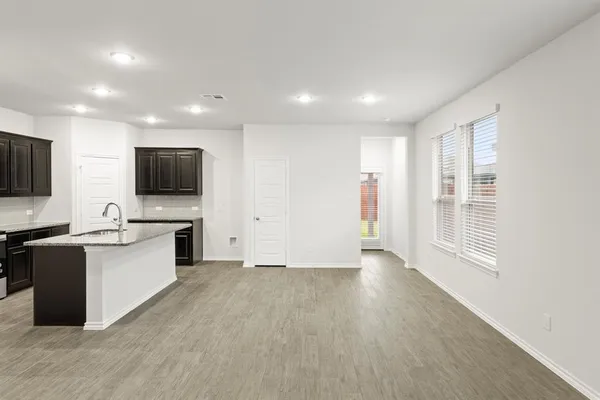 a view of a electric appliances in kitchen and empty room with wooden floor